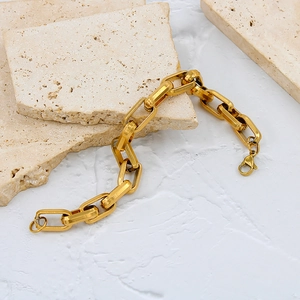 Detailed close-up of a bold gold stainless steel chain bracelet with a secure lobster clasp