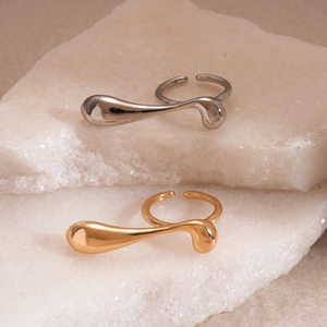 Minimalist fluid geometric open rings in gold and silver finish on natural stone slabs