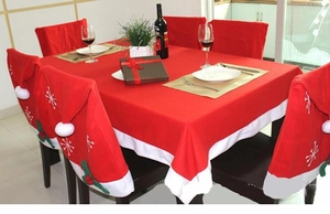 Detail of red Christmas table cloth and snowflake hat chair covers for festive dining decor