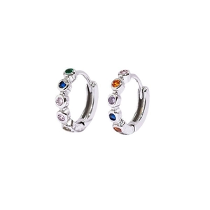 Macro detail of silver mini hoop earrings featuring multi-colored gemstones on white background