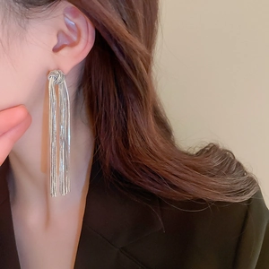 Close-up of elegant silver tassel drop earrings with metal knot design on a female model