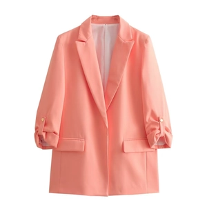 Detail of coral orange blazer showing folded cuffs with gold buttons and flap pockets