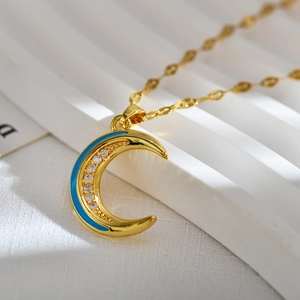 Golden crescent moon necklace with blue enamel and sparkling zircon on white background