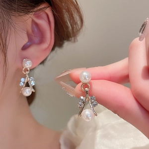 Close-up of elegant pearl and diamond-studded gold earrings worn by a model