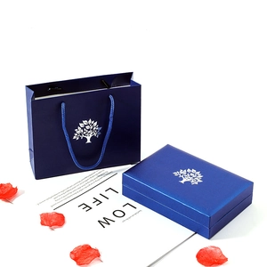 Royal blue jewelry gift box and matching paper bag with silver tree logo on white background