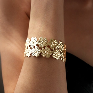 Detailed macro view of a gold-plated double-layer floral cuff bracelet on wrist