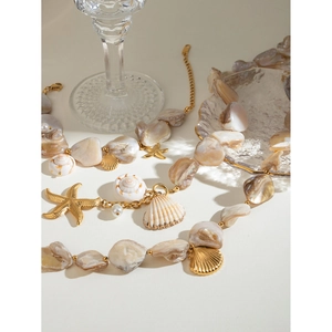 Detail of 18k gold stainless steel jewelry with shell starfish and conch charms