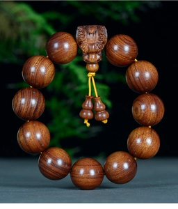Détail de perles en bois de Dalbergia poli avec créature sculptée et pompons jaunes décoratifs