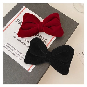 Red and black velvet bow hair clips for girls set on a minimalist fashion book background