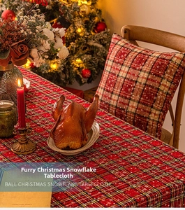 Detailed close-up of red plaid Christmas tablecloth with snowflake patterns and festive decor