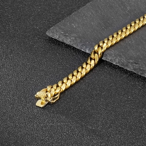 Top view of a gold 8mm Cuban link bracelet with a box clasp on a dark stone surface