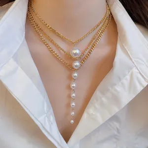 Three-layer gold chain necklace with vertical linear pearl pendants on a model