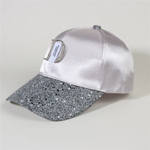 Detail of satin baseball cap featuring rhinestone metal D logo and paint splatter brim