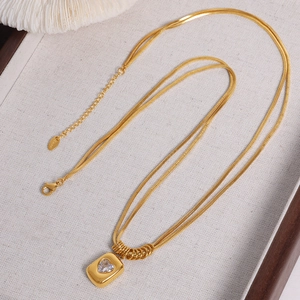 Double-layered gold snake chain necklace with heart zircon pendant on linen display tray