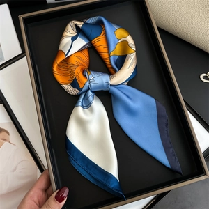 Close-up of elegant floral silk scarf with blue and orange prints in a gift box