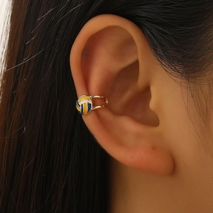 Κοντινό πλάνο χρυσού ear cuff βόλεϊ με μπλε κίτρινο λευκό σμάλτο σε γυναικείο αυτί