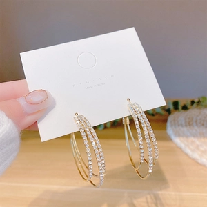 Close-up of triple-layered golden earrings with pavé-set zircons on a display card