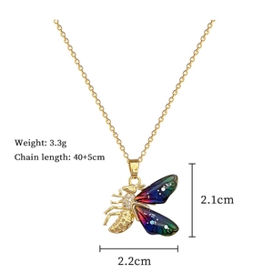 Macro shot of cicada pendant with enamel wings and size specs: 2.1cm x 2.2cm
