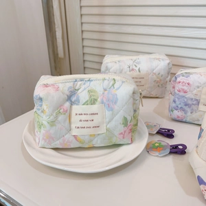 Close-up of quilted floral cotton makeup bag on a white ceramic plate