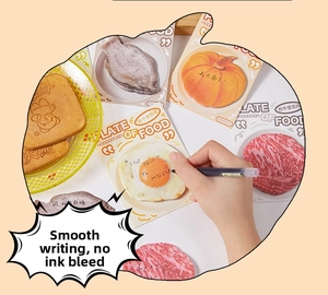 Close-up of hand writing on creative fried egg shaped sticky notes for DIY scrapbooking