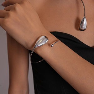 Detailed view of silver metallic teardrop bracelet with reflective mirror finish on wrist