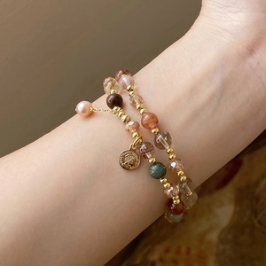 Detailed close-up of double-layer beaded bracelet with natural stones and coin pendant