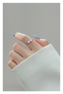 Close-up of a silver bow ring with spiral band texture on a model's finger