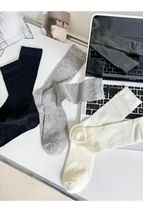 Three pairs of ribbed knit cotton socks in black, grey and beige on a desk