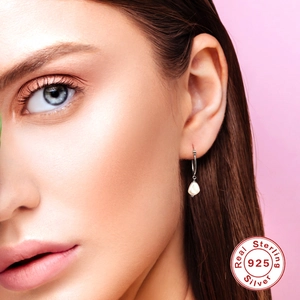 Elegant S925 sterling silver drop earrings with baroque pearls on model with pink background