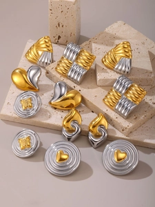 Close-up of geometric two-tone earrings on travertine stone with 80s vintage style