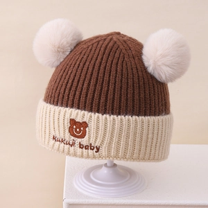 Detailansicht der Winter-Strickmütze für Babys mit zwei Pompons und Bärenstickerei