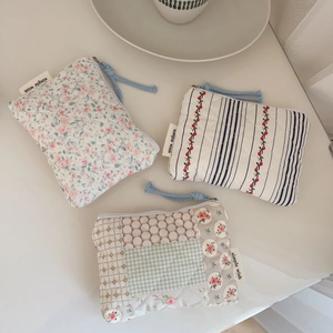 Three vintage floral quilted cotton coin purses with blue braided zipper pulls on a desk
