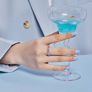 Close-up of S925 silver ring with colorful zircons worn by model holding a cocktail