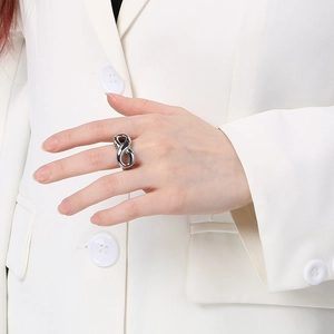 Detail of silver infinity shaped stainless steel ring worn on model hand with white suit