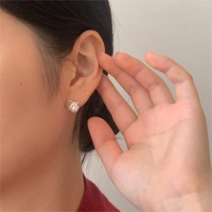 Detail of 925 sterling silver bowknot pearl earrings worn on a model's ear