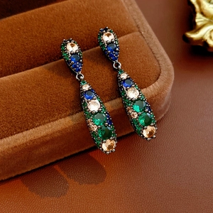 Détail macro de boucles d'oreilles vintage en goutte avec zircons émeraude et saphir