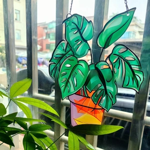 Detailed acrylic suncatcher showing a vibrant green monstera leaf with metal hanging chain
