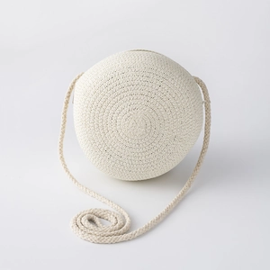 Détail du sac à bandoulière rond en paille tissée blanche avec texture artisanale