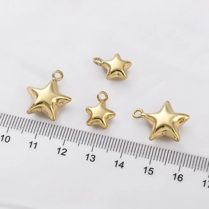Detailed view of 14K gold-filled star charms with a ruler showing various small sizes
