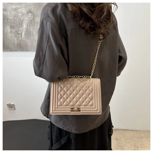 Detail view of the beige quilted crossbody bag with golden chain and diamond pattern