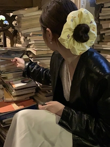 Dettaglio dell'elastico scrunchie giallo con piccoli fiori viola e arancioni