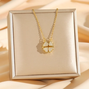 Golden convertible four-leaf clover heart necklace with sparkling crystals on silk background