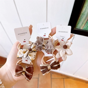 Detail showing five different fabric bow hair ties including stripes and floral patterns