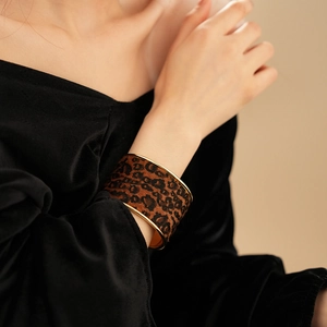 Close-up of wide leopard print bangle with golden metal edges on model wrist