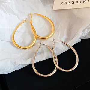 Minimalist oval metal hoop earrings set in polished gold and silver finishes