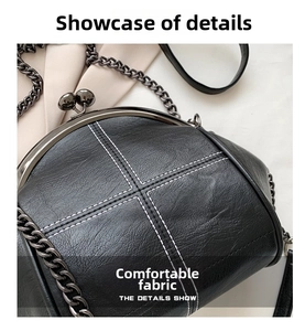 Close-up of black shell bag featuring white cross-stitching and metal clasp detail