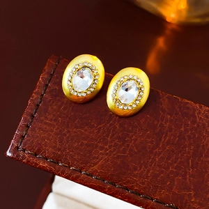 Macro view of gold oval vintage earrings with inlaid diamonds on brown leather