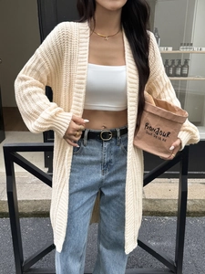 Dettaglio di un cardigan lungo in maglia crema con trama spessa e stile casual raffinato
