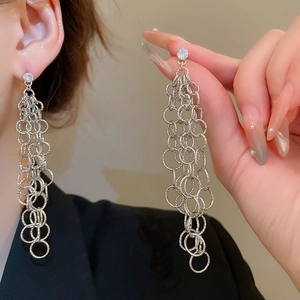 Gros plan de longues boucles d'oreilles pompons argentées avec strass et anneaux