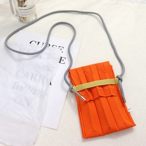 Detail view of the orange knitted pleated phone bag with gray knotted shoulder strap